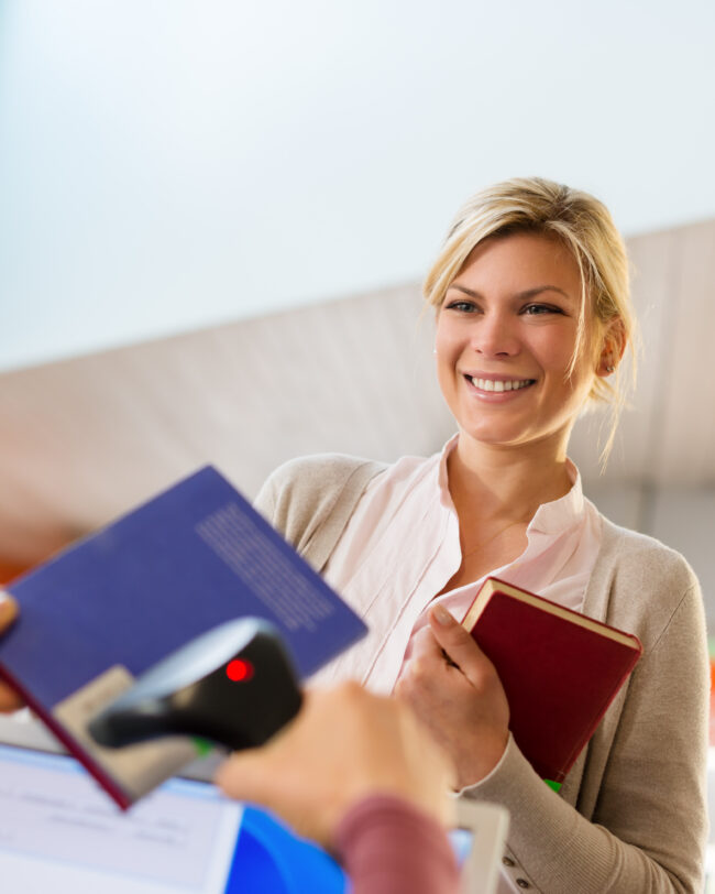 Portrait Of Young Female College Student Returning Book To Library