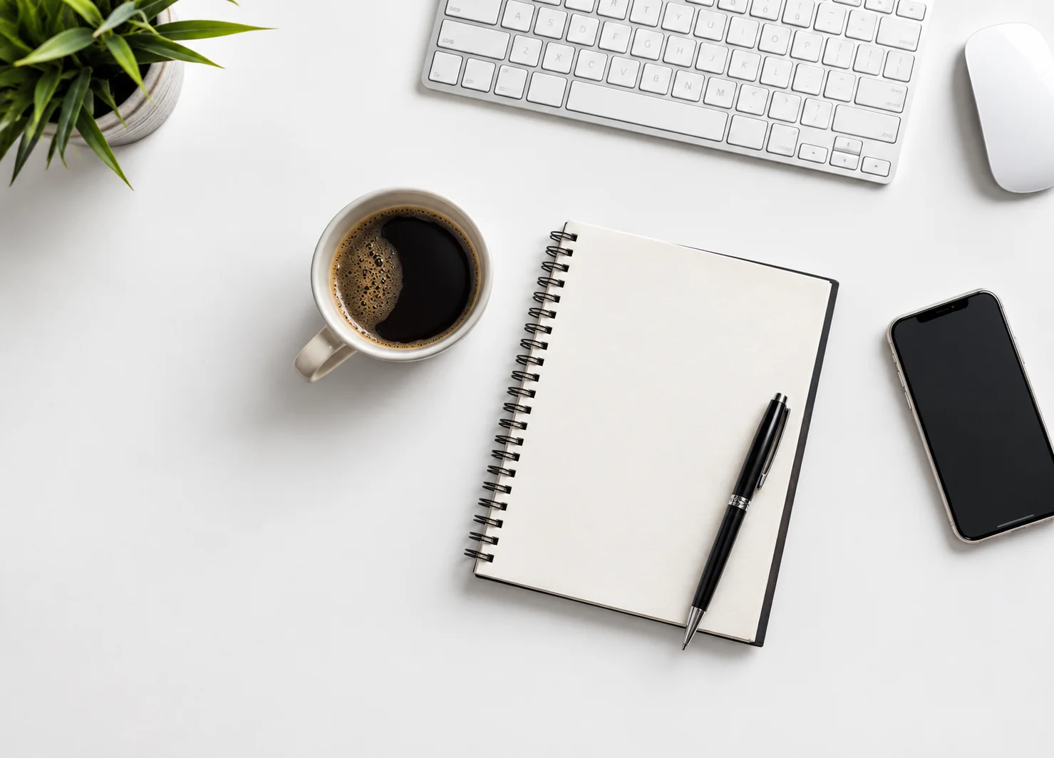 Birds eye view of an office desk with notepad, coffee and laptop
